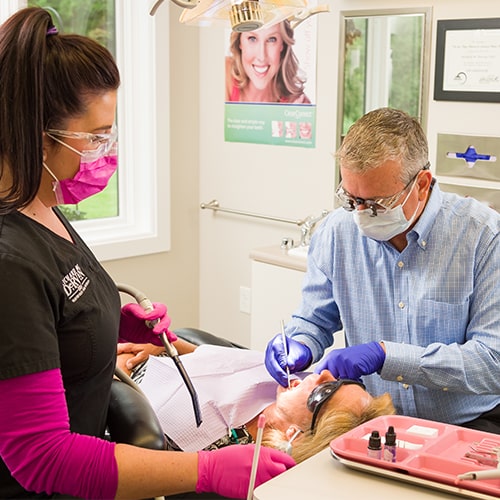 Dr. Dervin performing dental work on patient with dental assistant.